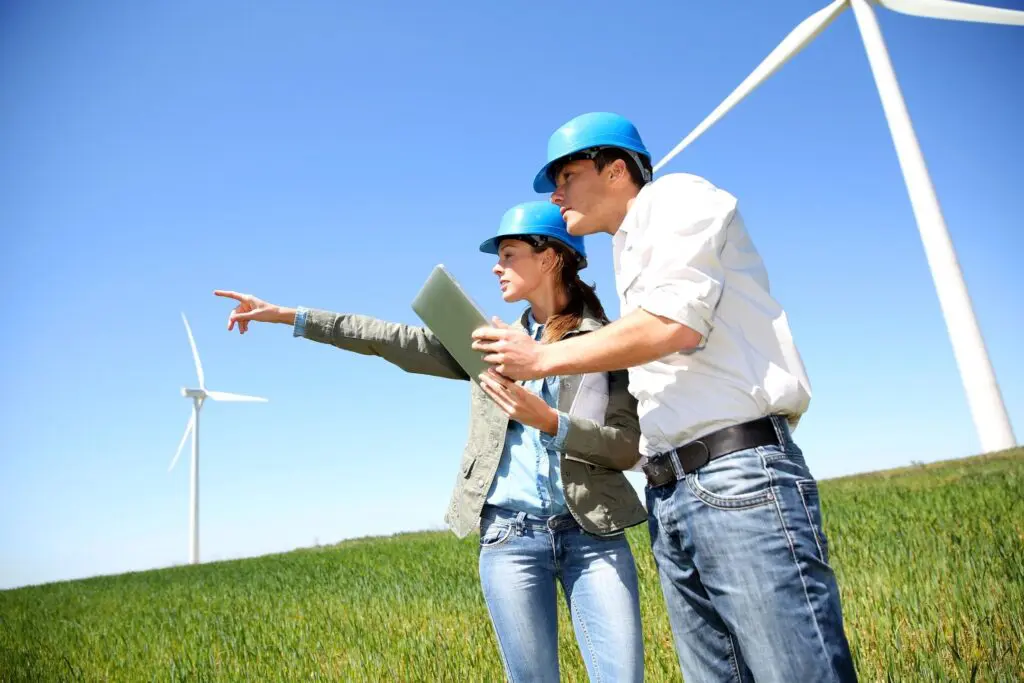 A man and woman standing in front of wind turbines.