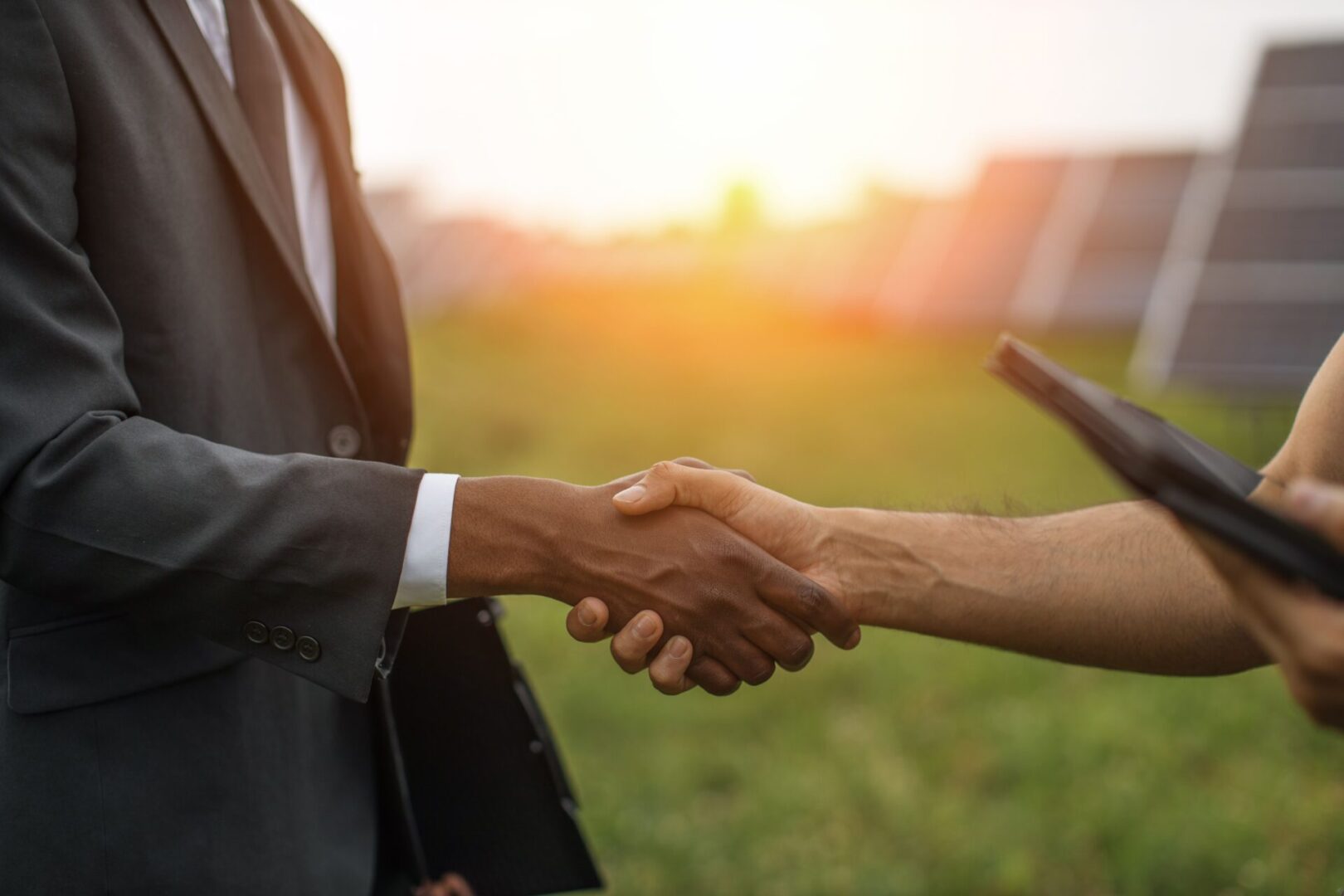 Two people shaking hands in a field.